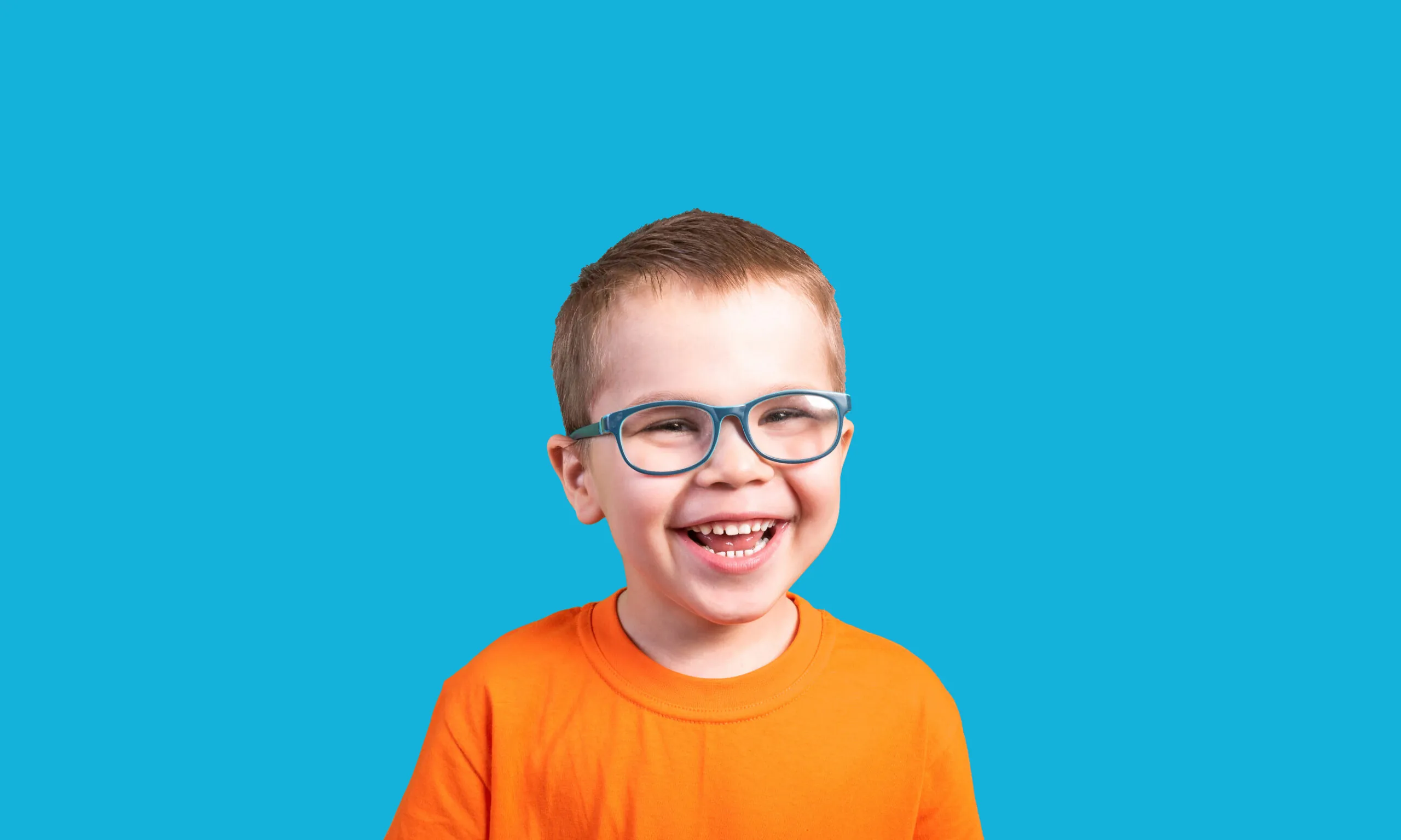 Young boy with glasses smiling.